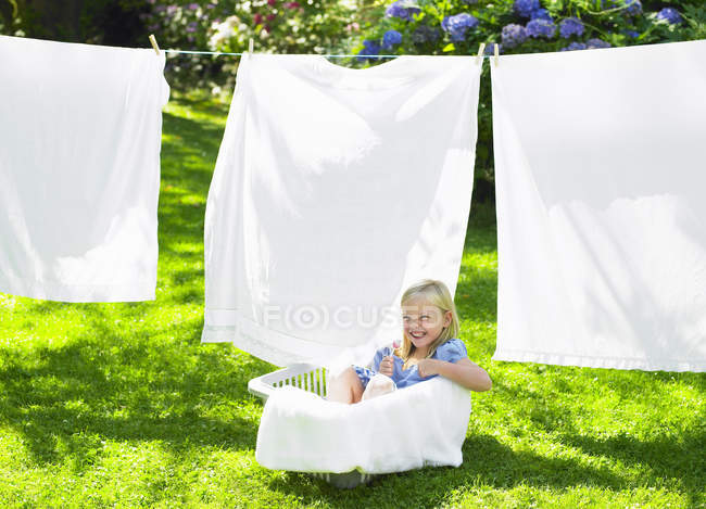 Chica jugando en la cesta de la ropa - foto de stock