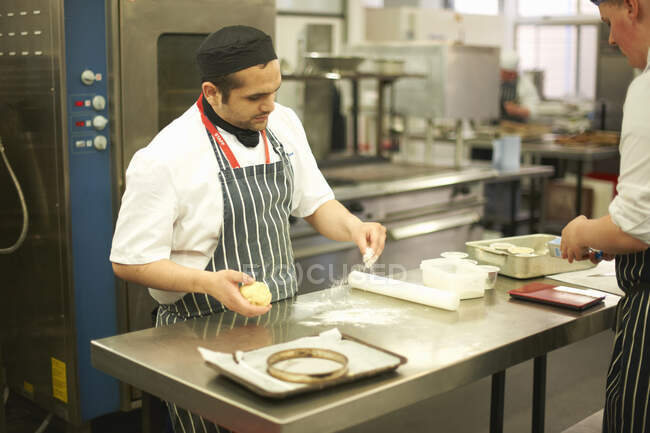 Chef lecturer demonstrating technique to teenage catering student at kitchen counter — Stock Photo