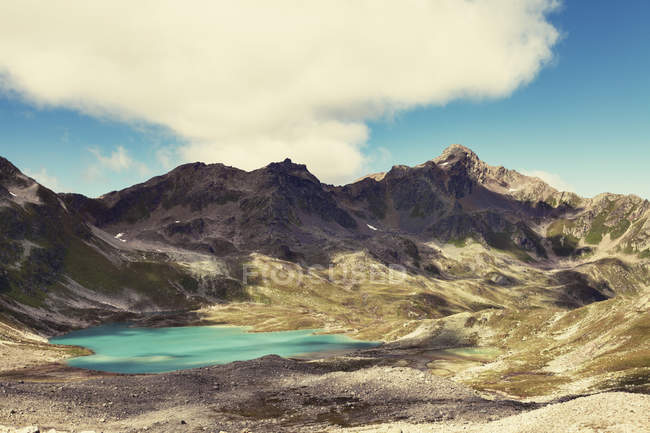 Gama de montanhas com lago azul e céu nublado — Fotografia de Stock