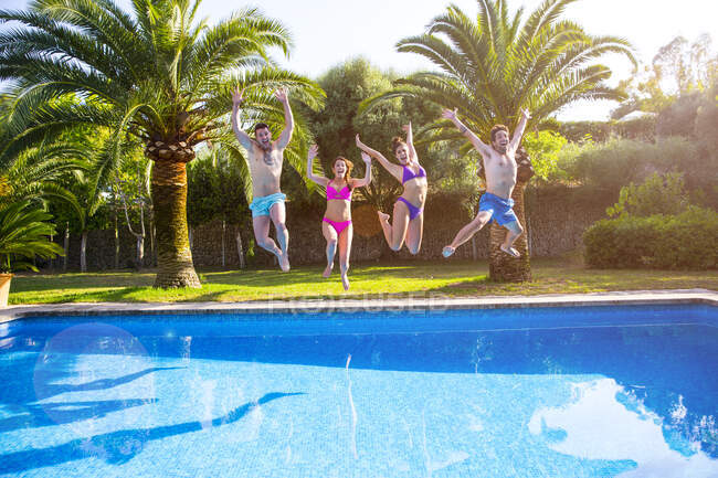 Friends jumping in swimming pool — Stock Photo