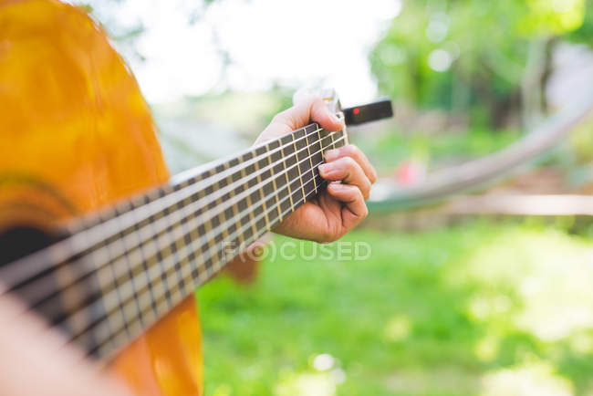 Мужские руки играют на акустической гитаре в саду — стоковое фото