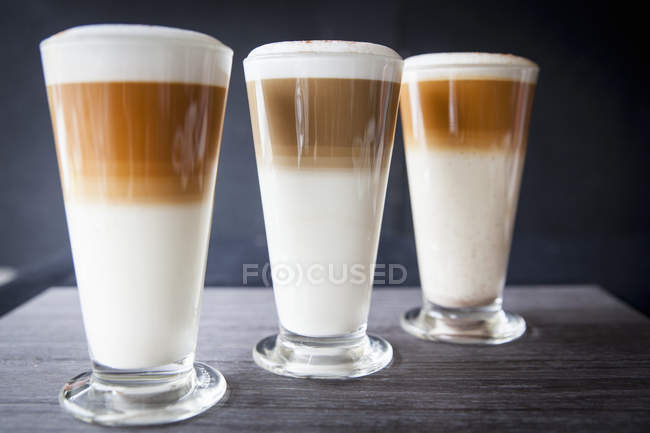 Three glasses of latte macchiato on table — Stock Photo