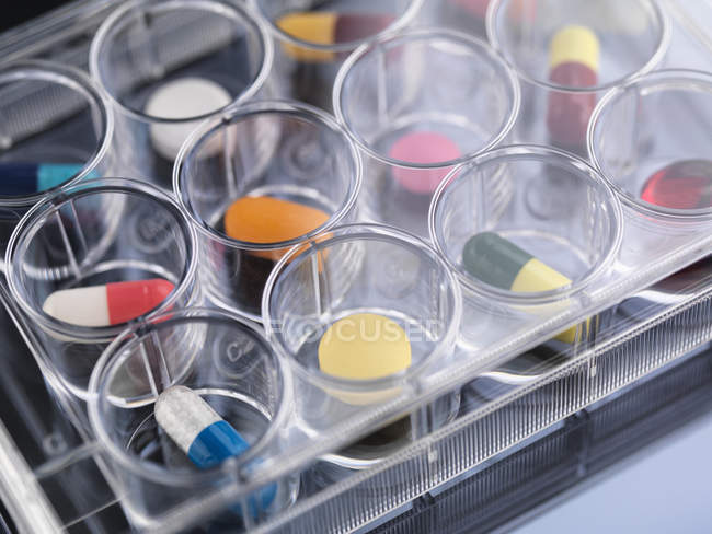 Investigación farmacéutica, primer plano de la variedad de medicamentos médicos en una bandeja de múltiples pozos para pruebas de laboratorio - foto de stock