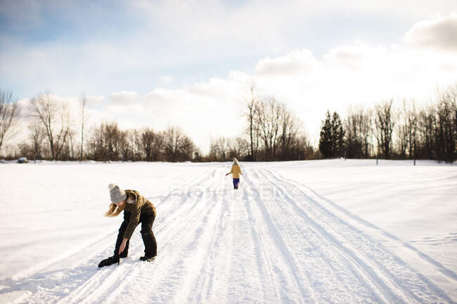 Mädchen nimmt Fäustling auf schneebedecktem Weg auf, Lakefield, Ontario, Kanada — Stockfoto