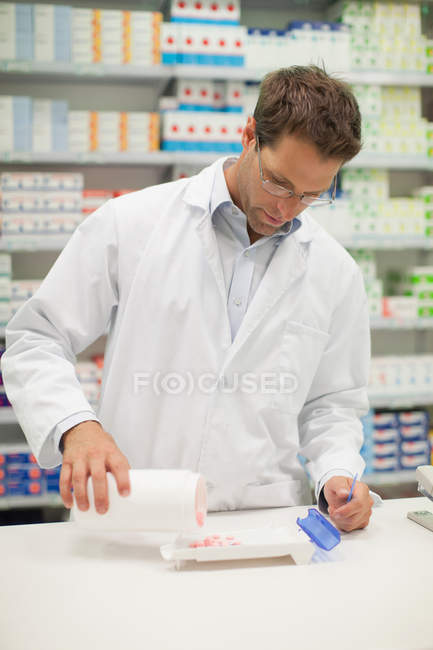 Farmacéutico contando pastillas en el mostrador - foto de stock