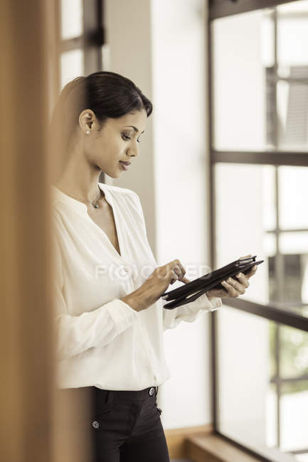 Jovem empresária usando tablet digital no escritório — Fotografia de Stock