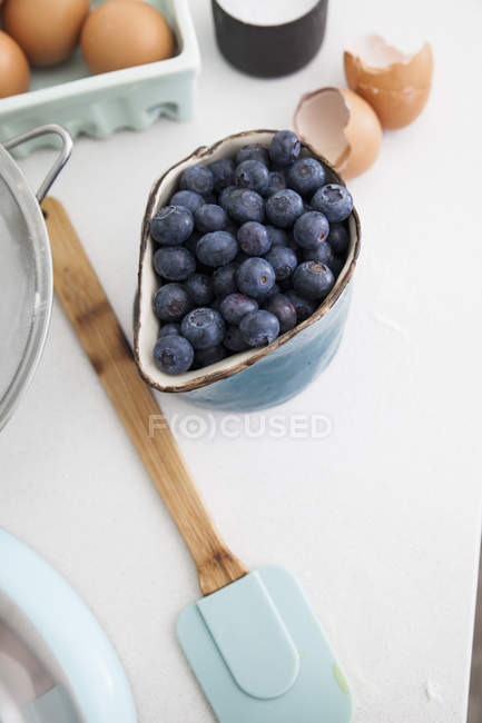 Tasse Blaubeeren und Karton mit Eiern auf der Küchentheke — Stockfoto