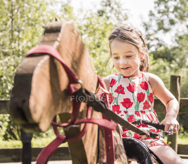 Девушка на деревянной лошади хобби улыбается — стоковое фото