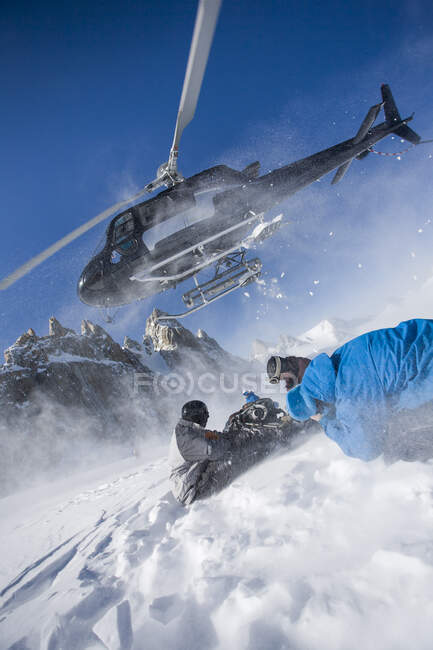 Elicottero in partenza da snowboarder maschi in montagna, Trento, Alpi svizzere, Svizzera — Foto stock