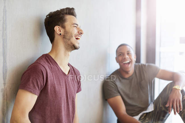 Два молодых студента в учебном пространстве смеются над высшим учебным заведением — стоковое фото
