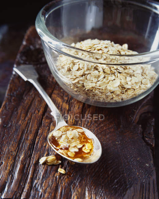 Honey and porridge oats on spoon on table — Stock Photo