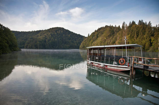 Nave traghetto al molo di legno nel lago tranquillo — Foto stock