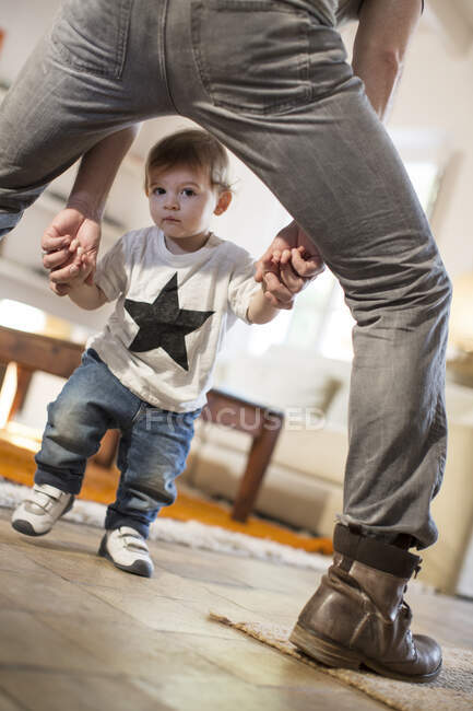Взгляд сквозь отцовские ноги мальчика, смотрящего в камеру — стоковое фото