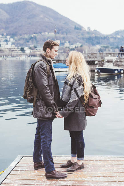 Романтическая молодая пара смотрит друг на друга на пирсе, озеро Комо, Италия — стоковое фото