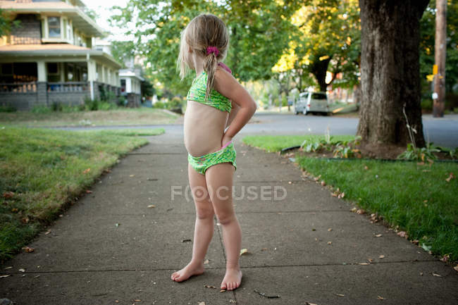 Young girl on pavement in bikini, looking behind — Stock Photo