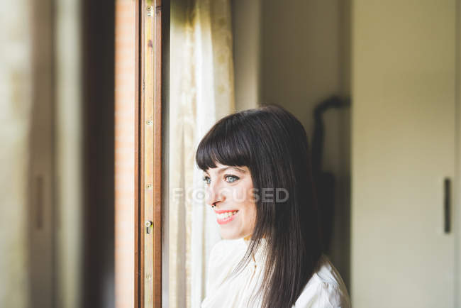 Молода жінка дивиться з вікна — стокове фото