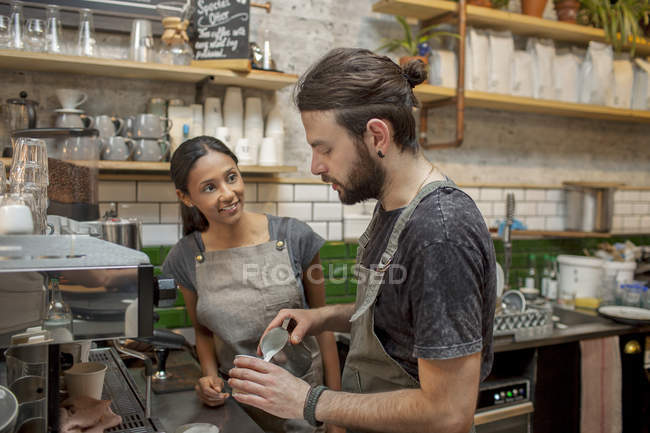 Baristas masculinos y femeninos preparando café en la cafetería - foto de stock