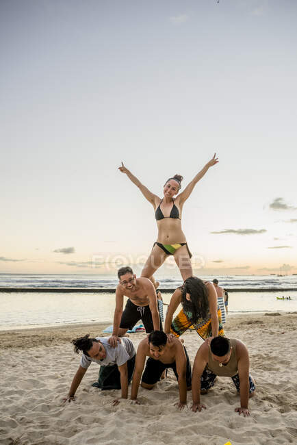 Seis amigos adultos formando pirâmide humana em Waikiki Beach, Havaí, EUA — Fotografia de Stock