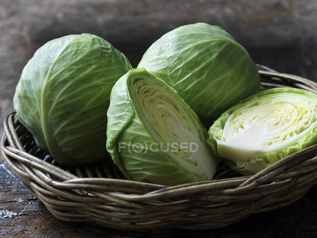 Whole and halved fresh baby cabbages in basket — Stock Photo