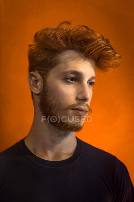 Porträt eines jungen Mannes mit roten Haaren vor orangefarbenem Hintergrund — Stockfoto