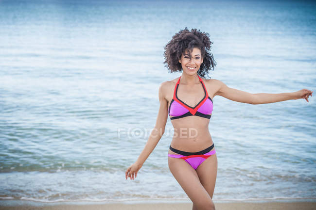 Hermosa joven con bikini rosa bailando en la playa, Costa Rei, Cerdeña, Italia - foto de stock