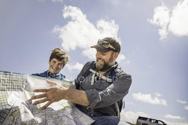 Father and teenage son on road trip reading folding map, Cody, Wyoming, USA — Stock Photo