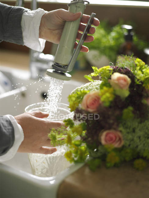 Abgeschnittenes Bild einer Frau, die Vase an der Spüle mit Wasser füllt — Stockfoto