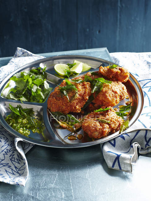 Spicy deep fried chicken dish with greens — Stock Photo