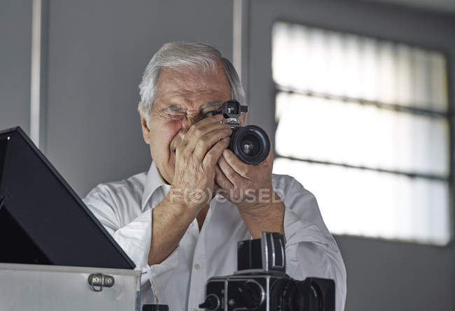Senior schaut durch Kamera — Stockfoto