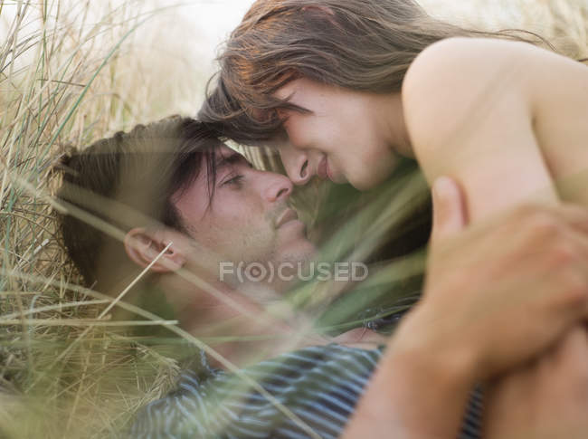 Couple couché dans l'herbe baisers — Photo de stock