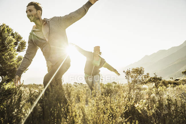 Пара бегущих в поле, с распростертыми объятьями — стоковое фото
