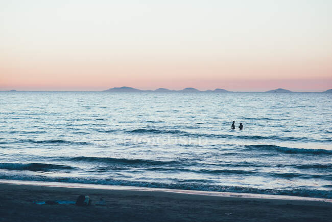 Distant people waist deep in ocean, Sorso, Sassari, Italy — Stock Photo