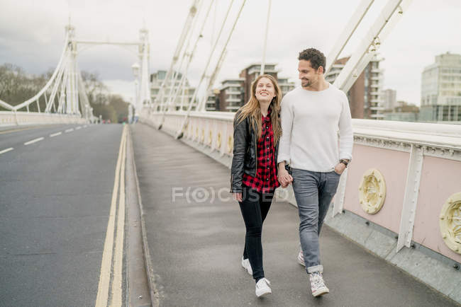 Молодая счастливая пара прогуливается по мосту, Баттерси Парк, Лондон, Великобритания — стоковое фото