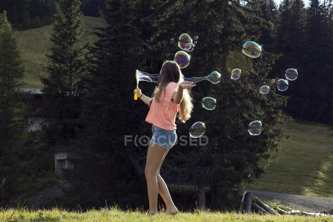 Jeune femme soufflant des bulles dans le champ, Sattelbergalm, Tyrol, Autriche — Photo de stock