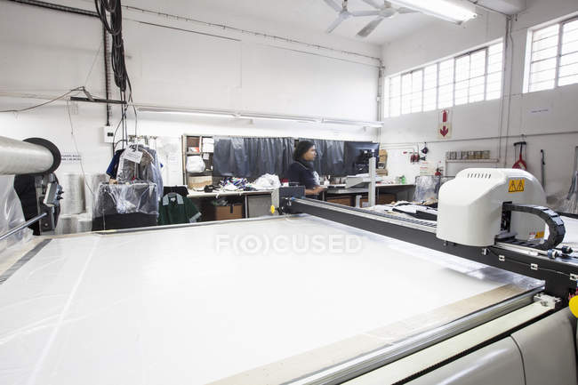 Máquina de corte padrão e trabalhador de fábrica na fábrica de roupas — Fotografia de Stock