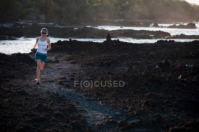 Woman running on rocky beach — Stock Photo