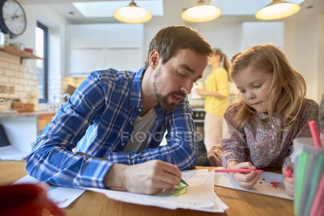 Mid adult man and daughter colouring at table in kitchen — Stock Photo