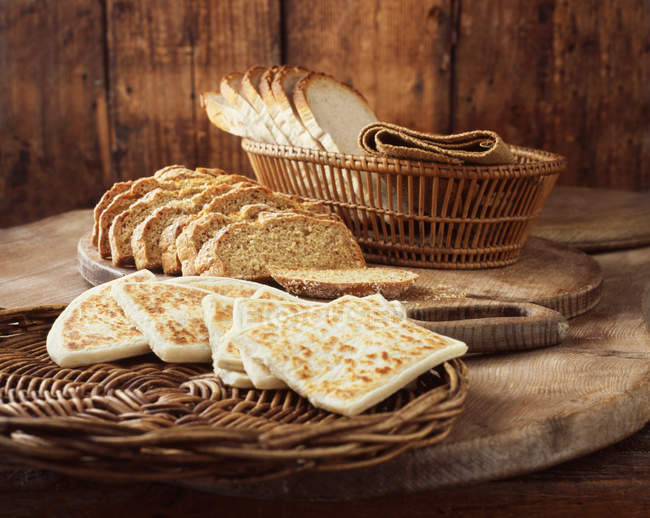 Flatbread, soda bread and white sliced bread on wooden cutting boards — Stock Photo