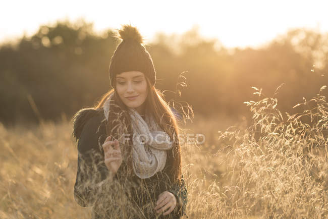 Молодая женщина в поле, смотрит на смартфон — стоковое фото