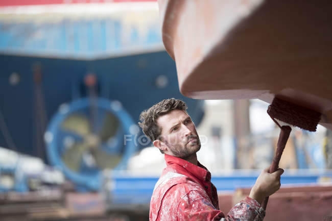 Barco masculino pintor rodillo pintura casco de barco en astillero pintores - foto de stock