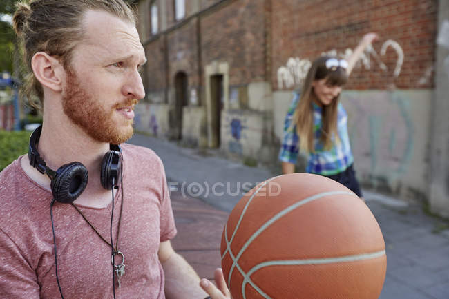 Young couple outdoors, throwing basketball — Stock Photo