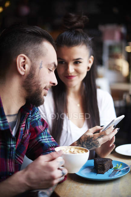 Pareja con smartphone en la cafetería - foto de stock