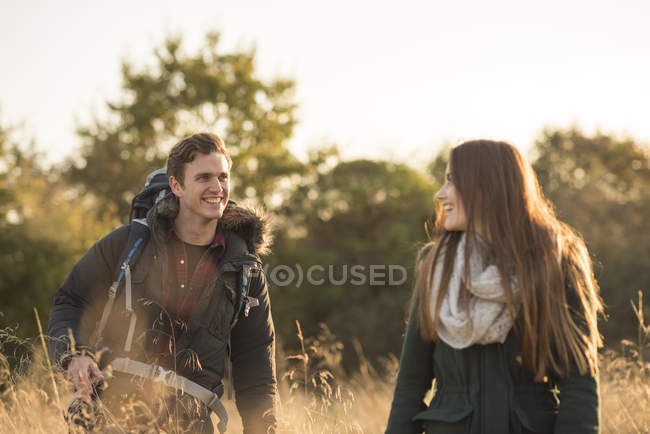 Jovem casal caminhando através do campo — Fotografia de Stock