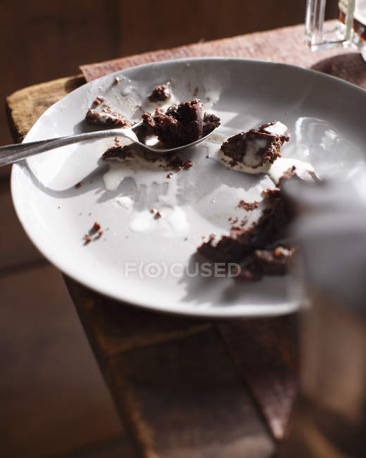 Briciole avanzate di torta al cioccolato con cucchiaio sul piatto — Foto stock