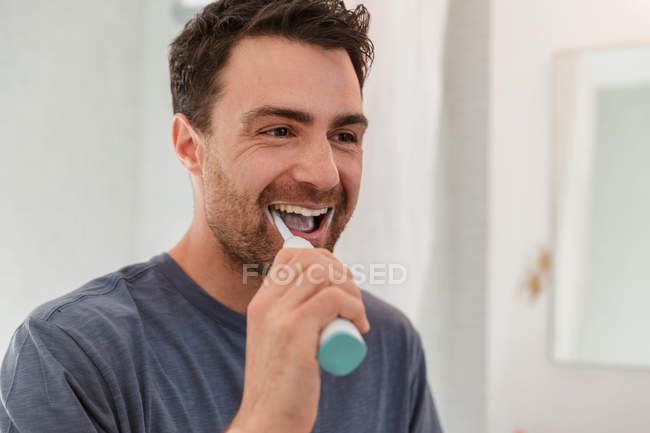 Mann putzt Zähne und lächelt in Spiegel — Stockfoto