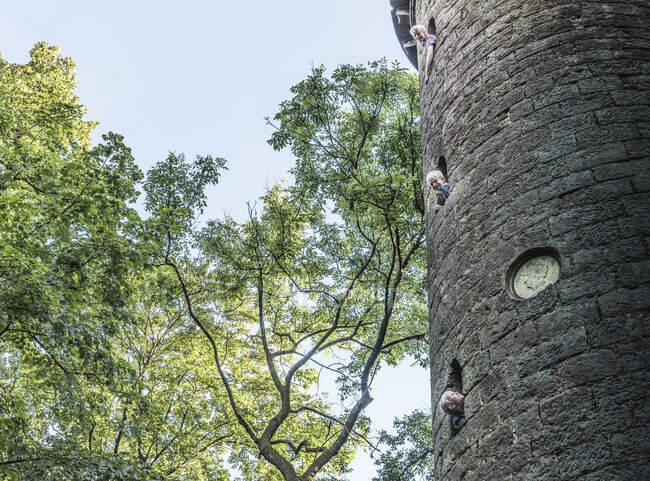 Boys leaning out of stone tower windows — Stock Photo