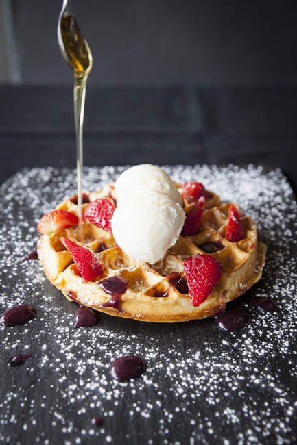 Colher derramando xarope de bordo sobre morangos e sorvete waffle — Fotografia de Stock
