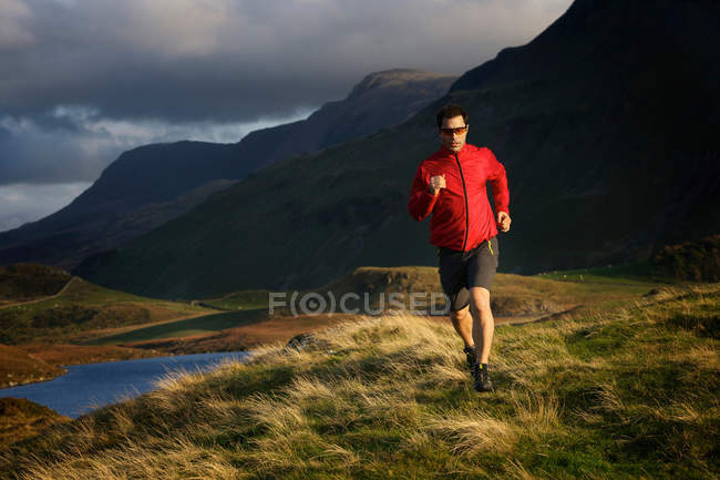 Hiker running on grassy hillside — Stock Photo