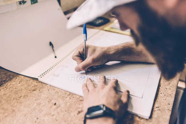 Close up of man writing on calendar at gym reception desk — Stock Photo