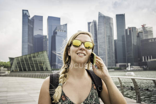 Мбаппе с мобильным телефоном, горизонт Сингапура, Марина Бэй на заднем плане — стоковое фото
